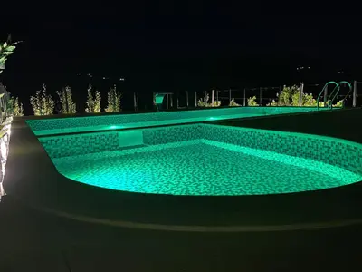 a swimming pool lit up at night at Pejovic Residence Budva in Budva