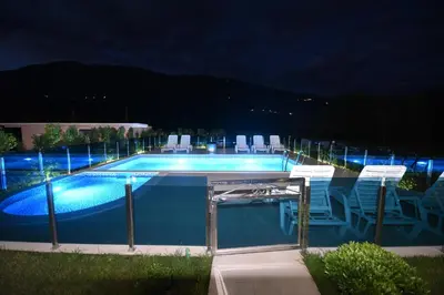 a swimming pool at night with chairs and lights at Pejovic Residence Budva in Budva