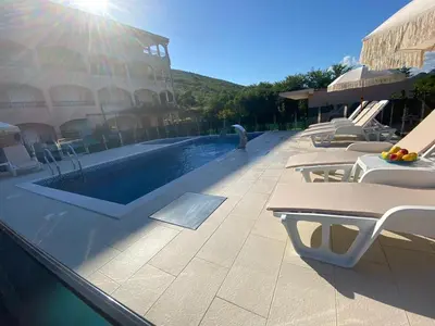 a swimming pool with tables and chairs next to a building at Pejovic Residence Budva in Budva