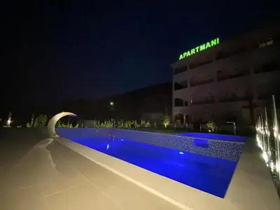 a swimming pool in front of a building at night at Pejovic Residence Budva in Budva
