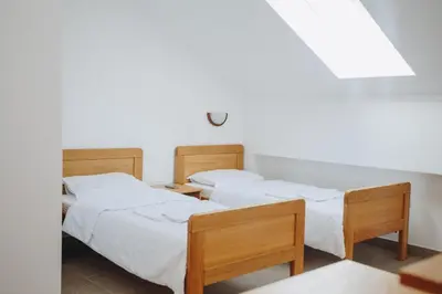 two beds in a room with white sheets at Eco Winery Lipovac Apartments in Cetinje