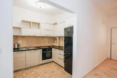a kitchen with white cabinets and a black refrigerator at Apartment near Ponta Nova of Rafailovici in Becici