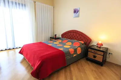 a bedroom with a bed with a red bedspread and a table at Villa Narcissus Montenegro KO Sveti Stefan in Sveti Stefan