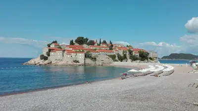a beach with chairs and umbrellas and a resort at Apartment-Hotel Vila Petrovic-Becici in Budva