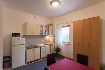 a kitchen with a white refrigerator and a table with chairs at Apartment-Hotel Vila Petrovic-Becici in Budva