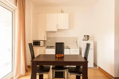 a dining room table with chairs and a kitchen at Apartment-Hotel Vila Petrovic-Becici in Budva