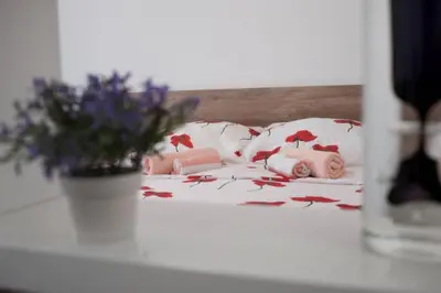 a bed with pink and white pillows and a vase with flowers at B&T Apartments in Budva
