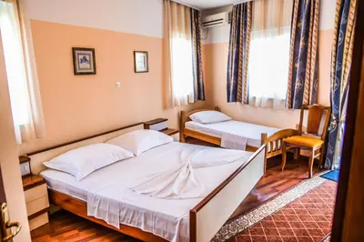 a hotel room with two beds and a chair at Eldorado Apartments in Ulcinj