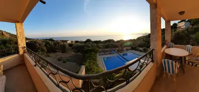 a balcony with a view of a pool and the sunset at Villa Lipski in Sveti Stefan