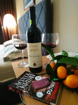 a bottle of wine on a table with a book and glasses at Villa Marija Ulcinj in Ulcinj