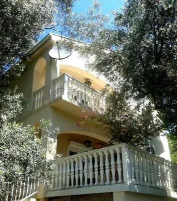 a white house with a white balcony and trees at Villa Marija Ulcinj in Ulcinj