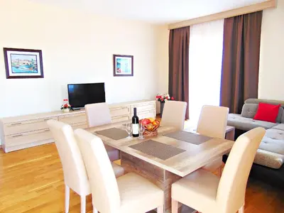 a living room with a dining room table with white chairs at ApartHotel Belvedere Residence Becici Budva in Budva