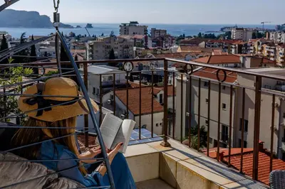 a woman sitting on a balcony looking at the city at Arvala Apartments in Budva