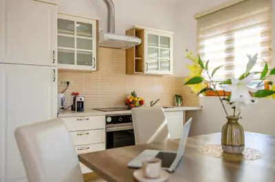 a kitchen with white cabinets and a wooden table at Arvala Apartments in Budva