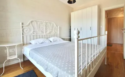 a bedroom with a white bed and a white crib at Albatros Apartments in Bar