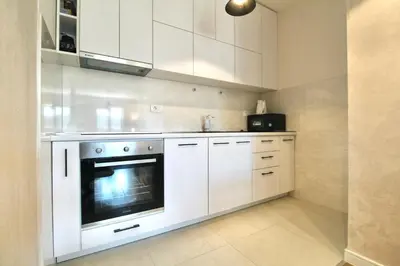 a white kitchen with white cabinets and a microwave at Albatros Apartments in Bar