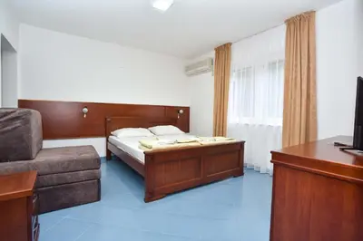 a bedroom with a bed and a couch and a television at Hotel Galeb in Čanj