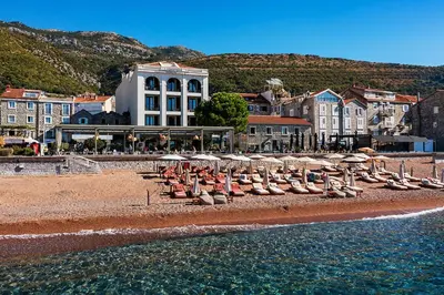 a group of umbrellas and chairs on a beach at Hotel Riva by Aycon in Petrovac na Moru