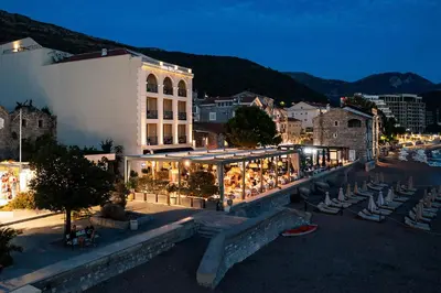 a city at night with a building and tables and chairs at Hotel Riva by Aycon in Petrovac na Moru
