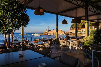a restaurant with tables and chairs next to the water at Hotel Riva by Aycon in Petrovac na Moru