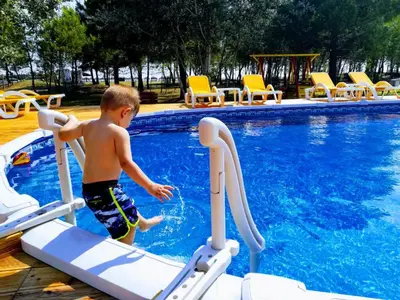 a young boy is going down a water slide in a swimming pool at MCM Camping in Ulcinj