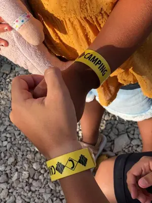 a person with yellowbands on their arm with a sign that saysulum at MCM Camping in Ulcinj