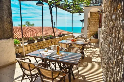 an outdoor patio with tables and chairs and the ocean at Villa Marinero in Ulcinj