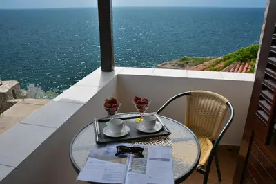 a table on a balcony with a view of the ocean at Villa Marinero in Ulcinj