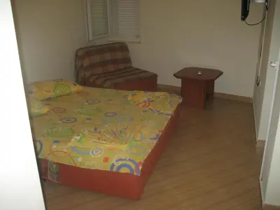 a small bedroom with a bed and a chair at Guest House Vila Mimoza in Ulcinj