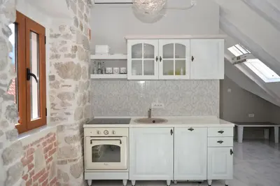 a kitchen with white cabinets and a sink and an oven at Palazzo Max and Alex Apartments in Kotor