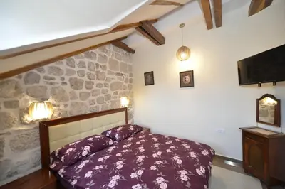 a bedroom with a bed and a stone wall at Palazzo Max and Alex Apartments in Kotor