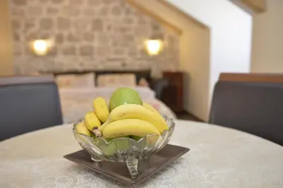 a glass bowl of bananas and fruit on a table at Palazzo Max and Alex Apartments in Kotor