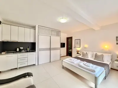 a bedroom with a large bed and a kitchen at Apartments Villa Stefan in Budva