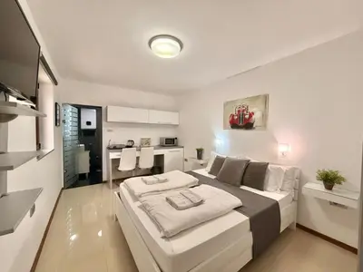 a bedroom with a large bed and a kitchen at Apartments Villa Stefan in Budva