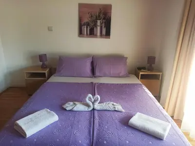 a purple bed with two towels and a pair of shoes at Apartments Mitende in Budva