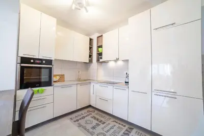 a white kitchen with white cabinets and a chair at Apartman Marija in Budva