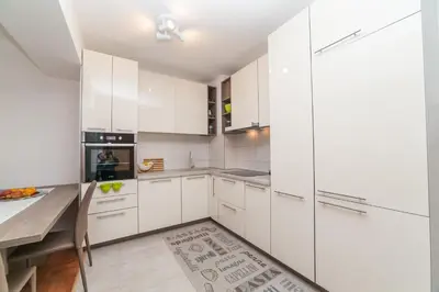 a white kitchen with white cabinets and a table at Apartman Marija in Budva
