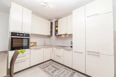 a white kitchen with white cabinets and a chair at Apartman Marija in Budva