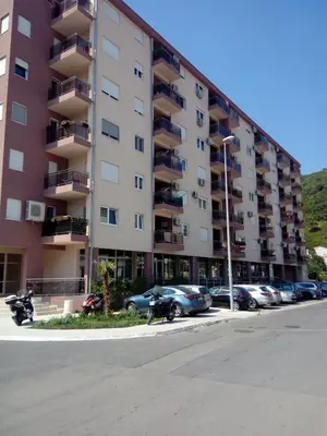 a large apartment building with cars parked in a parking lot at Apartman Marija in Budva