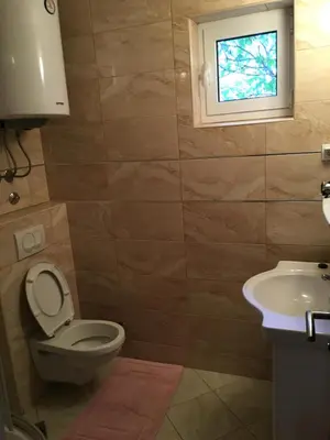 a bathroom with a toilet and a sink and a window at Apartments and Rooms Villa Gaga 3 in Budva