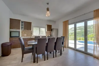 a kitchen and dining room with a table and chairs at Yokana Villa & Pool in Virpazar