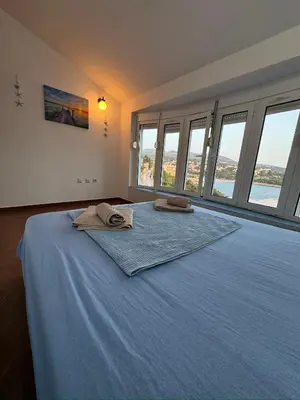 a bedroom with a bed with blue sheets and windows at Vila Vujošević in Utjeha