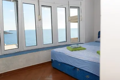 a bedroom with windows and a bed with a view of the ocean at Vila Vujošević in Utjeha
