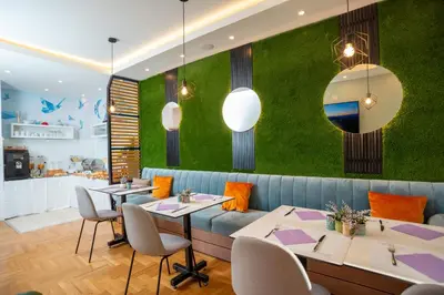 a restaurant with tables and a green wall at Peace 2 Apartments with parking in Budva