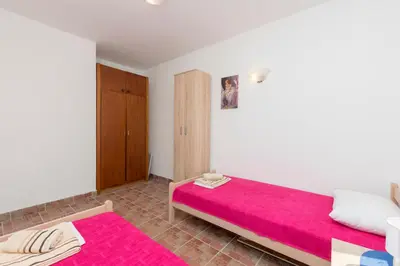 a bedroom with a pink bed and a cabinet at Apartment Carpe Diem 1 in Utjeha