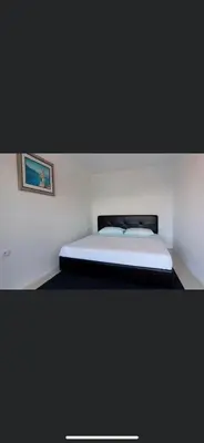 a bed in a white room with a picture on the wall at Apartments Feniks in Ulcinj