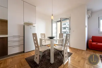 a dining room with a table and chairs and a red couch at Ancora 1 in Budva