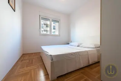a white bedroom with a bed and a window at Ancora 1 in Budva