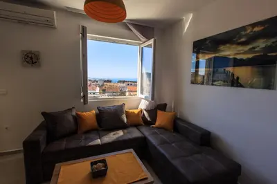 a living room with a couch and a large window at Apartments Aleksić in Bar