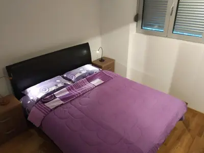 a purple bed with a black headboard in a bedroom at Apartments Svilen Konac in Budva